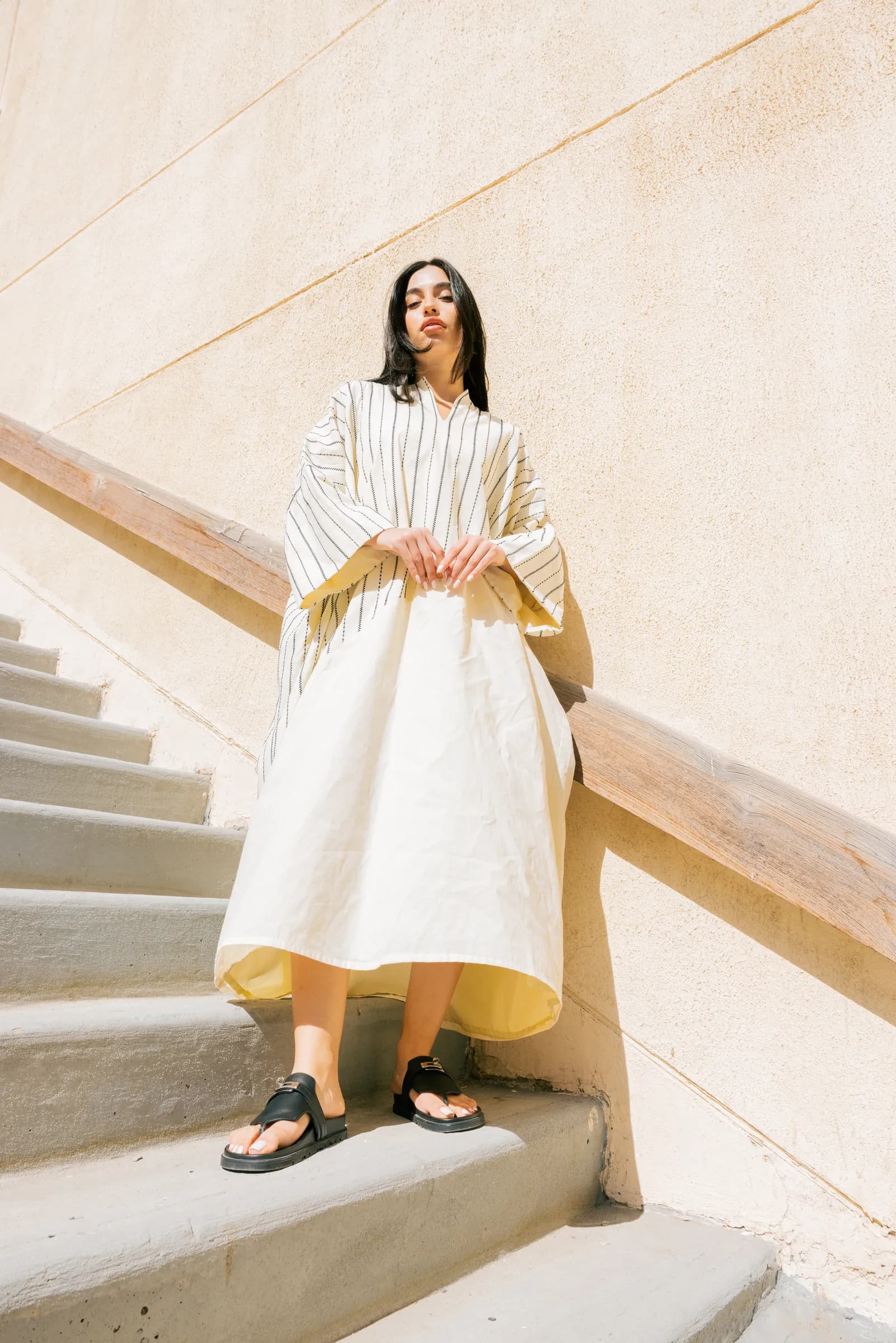 Model in an abaya posing against white walls in Kuwait