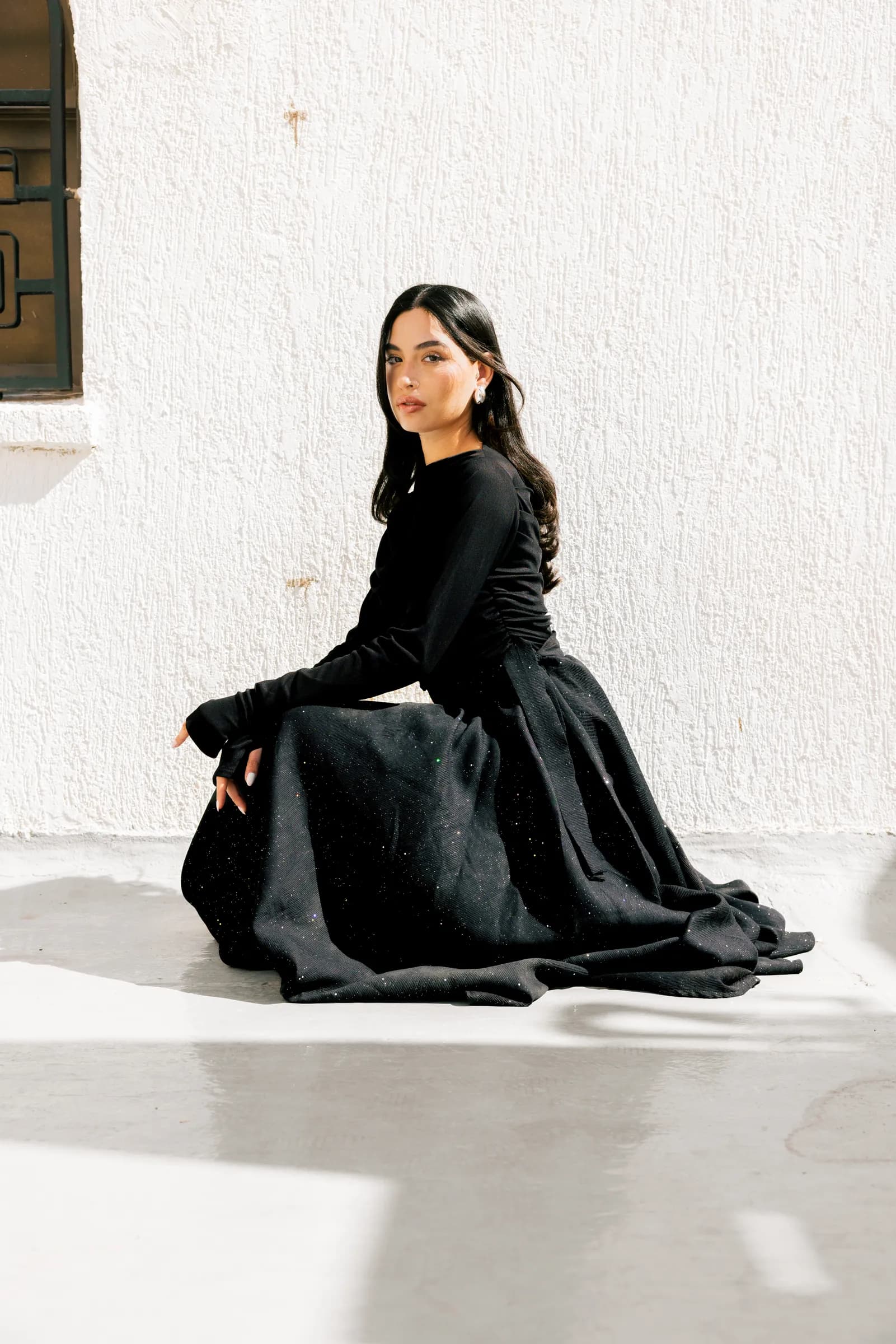 Model in an abaya posing against white walls in Kuwait