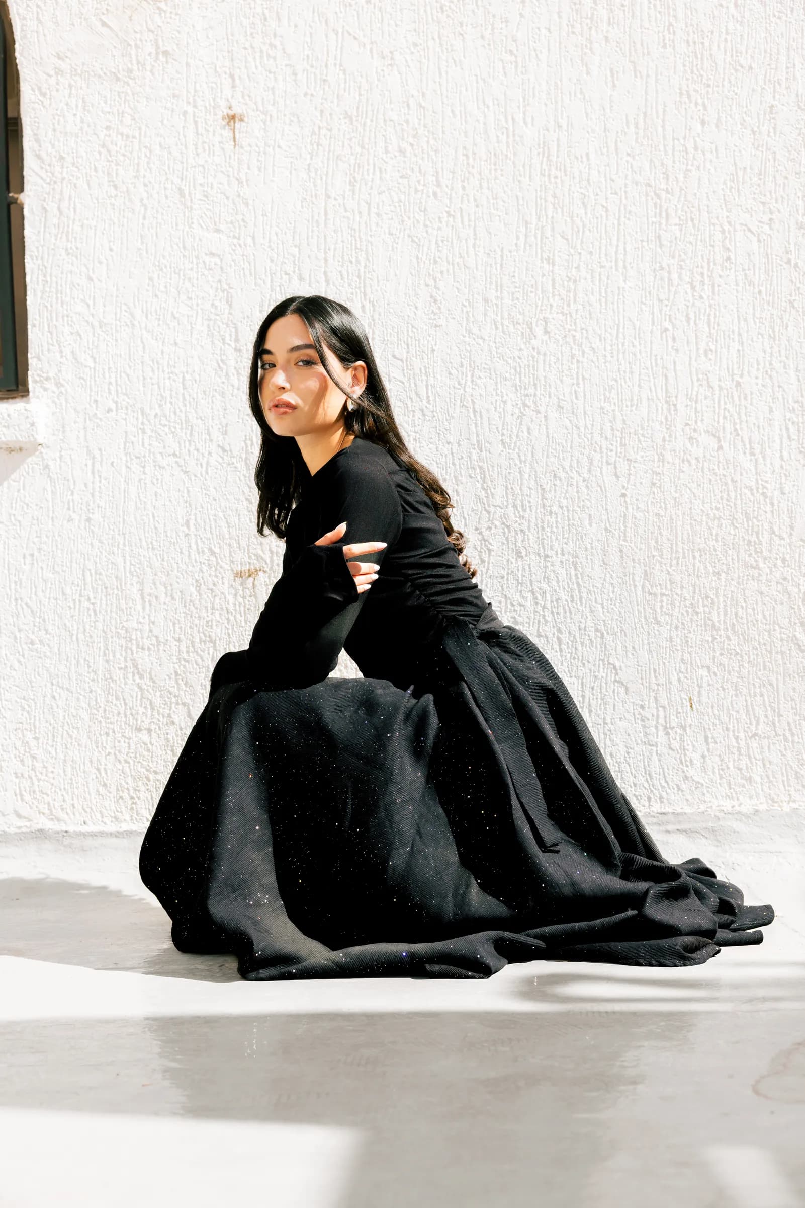 Model in an abaya posing against white walls in Kuwait