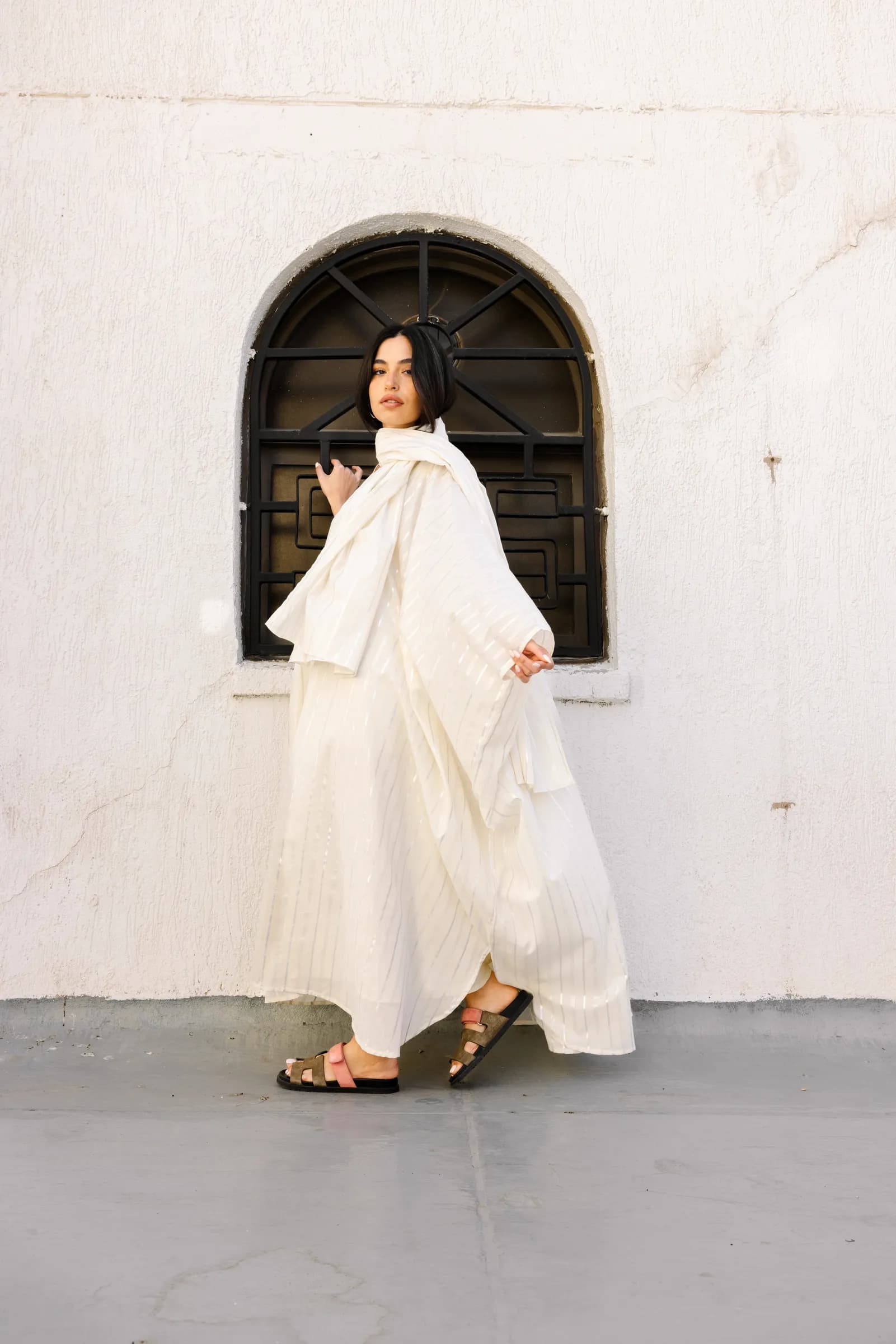Model in an abaya posing against white walls in Kuwait